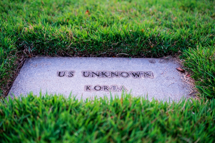 A flat stone marking reading "U.S. UNKNOWN - KOREA" is surrounding by grass.