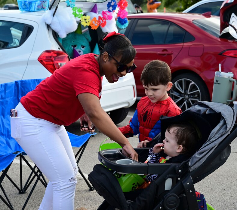U.S. Air Force Master Sgt. Tiffany Hollington passes out candy to families during the Ghoulfellow Trunk or Treat event hosted at the Louis F. Garland Fire Academy, Goodfellow Air Force Base, Texas, Oct. 28, 2023. Volunteers filled 35 parking spots at the fire academy, where they decorated their trunks and passed out treats to nearly 2,000 costumed attendees. (U.S. Air Force photo by Airman 1st Class Madison Collier)