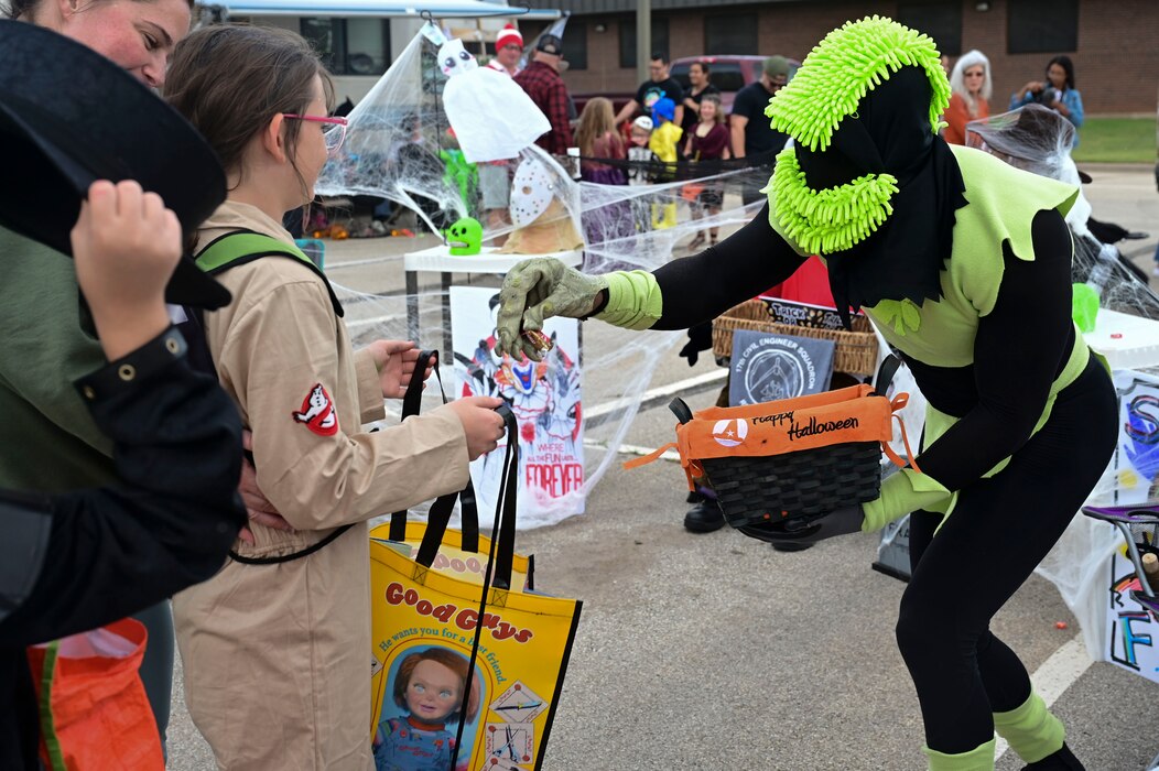 A volunteer passes out candy to families during the Ghoulfellow Trunk or Treat event hosted at the Louis F. Garland Fire Academy, Goodfellow Air Force Base, Texas, Oct. 28, 2023. Volunteers dressed up and passed out candy provided by the 17th Force Support Squadron to families who attended the event. (U.S. Air Force photo by Airman 1st Class Madison Collier)