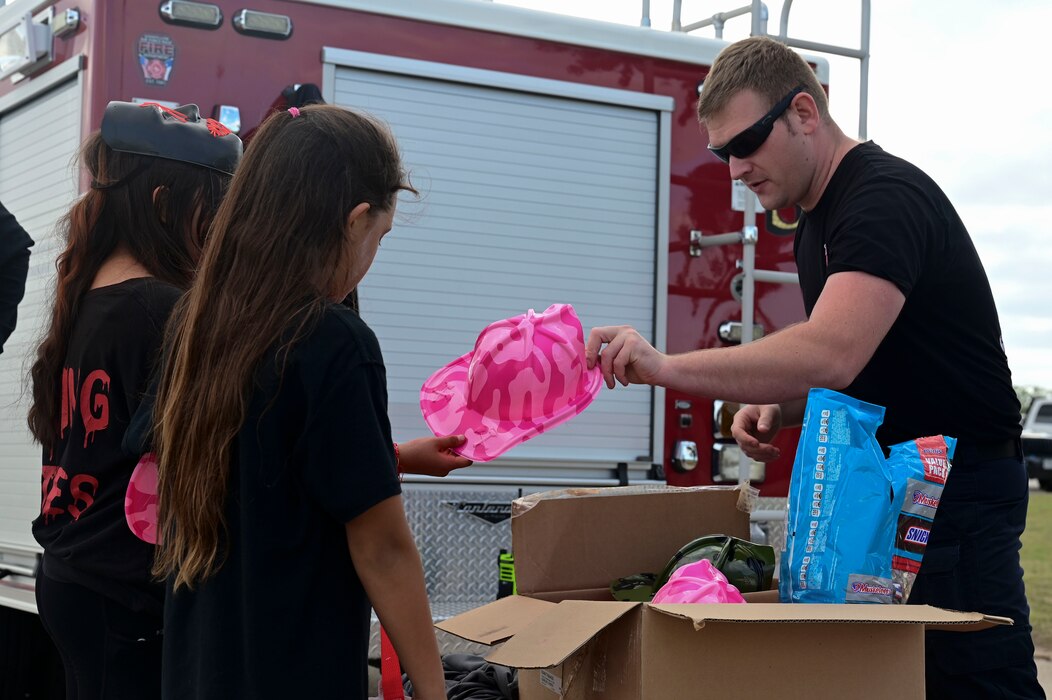 A member of the Goodfellow Air Force Base Fire Department passes out candy and goodies to families during the Ghoulfellow Trunk or Treat event hosted at the Louis F. Garland Fire Academy, Goodfellow Air Force Base, Texas, Oct. 28, 2023. Agencies and on-base groups brought goods and snacks to pass out to families. (U.S. Air Force photo by Airman 1st Class Madison Collier)
