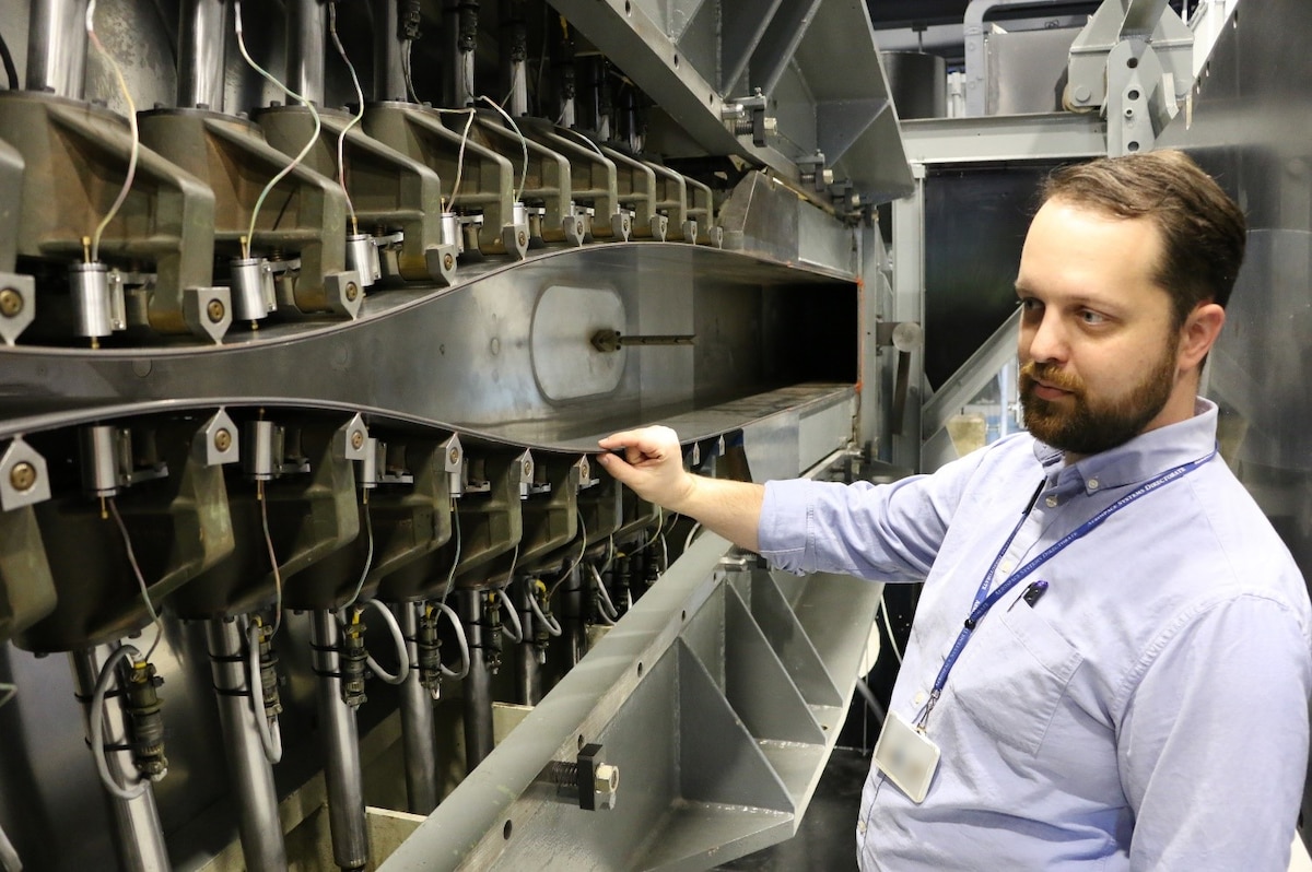Dr. Jerrod Hofferth, senior aerospace research engineer, Aerospace Systems Directorate, Air Force Research Laboratory, who served as the technical lead on the Tunnel D reactivation project, pointing out the Tunnel D flexible plate nozzle in June 2018. Hofferth was recognized as a 2024 Associate Fellow of the American Institute of Aeronautics and Astronautics, or AIAA, in a news release Oct. 3, 2023. (U.S. Air Force photo illustration / Bradley Hicks)