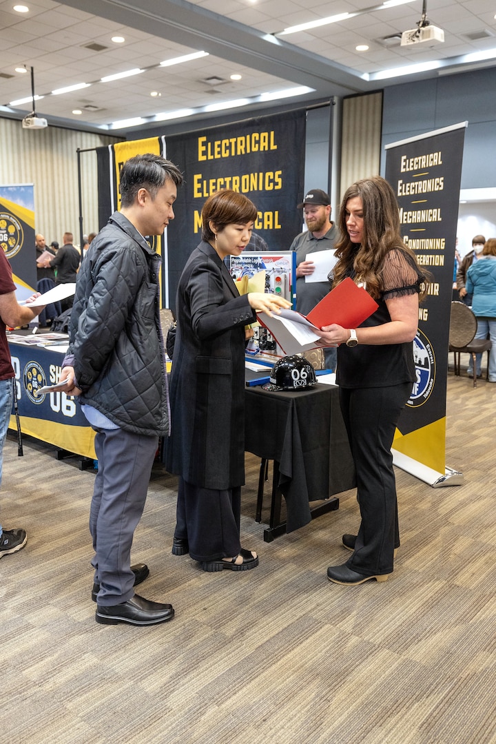 Melissa Brown, work lead, Shop 06, Tool Mechanics Maintenance Logistics, reviews a resume for job seeker Sunmi Hong, of Poulsbo, Washington, who attended the Puget Sound Naval Shipyard & Intermediate Maintenance Facility Hiring Fair Oct. 20, 2023, in downtown Bremerton, Washington, with her husband, Sungsoo Min. (U.S Navy Photo by Wendy Hallmark)