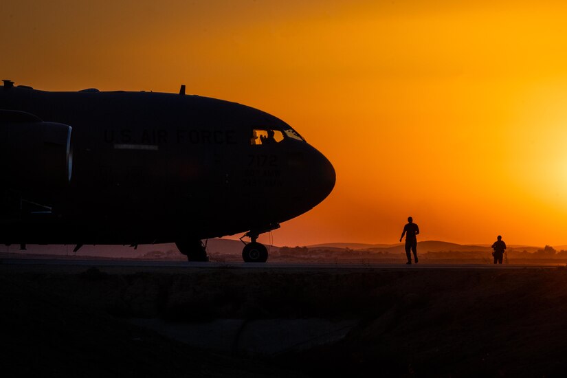 The silhouette of an aircraft on a flight line at sunset is shown.