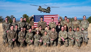 U.S. Guardians pose for a photo after a reenlistment ceremony, with a flag behind them.