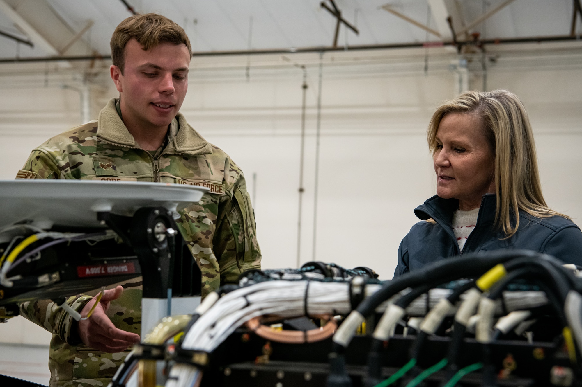 U.S. Air Force Senior Airman Zack Gore, 12th Aircraft Maintenance Unit MQ-9 avionics journeyman, explains the mechanics of the MQ-9 Reaper remotely piloted aircraft to Renee Russ, 27th Special Operations Wing honorary commander, during the 27th Special Operations Maintenance Group’s Honorary Commander’s Day at Cannon Air Force Base, N.M., Oct. 30, 2023. The intent of the honorary commander program is to establish a stronger relationship between members of the local community and the installation. (U.S. Air Force photo by Staff Sgt. Vernon R. Walter III)