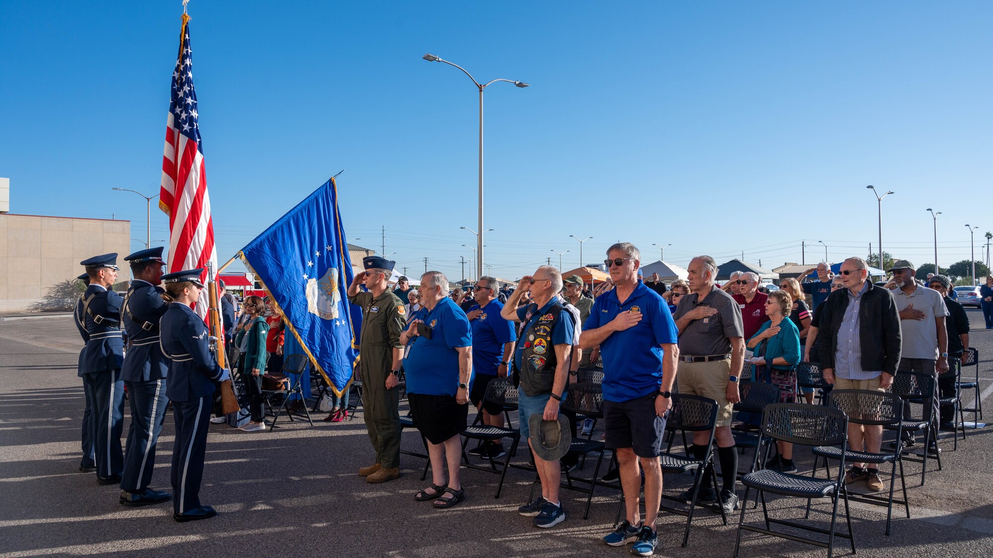 Retired and active-duty service members salute the colors during the singing of the national anthem at a retiree appreciation event October 21, 2023, at Luke Air Force Base, Arizona.