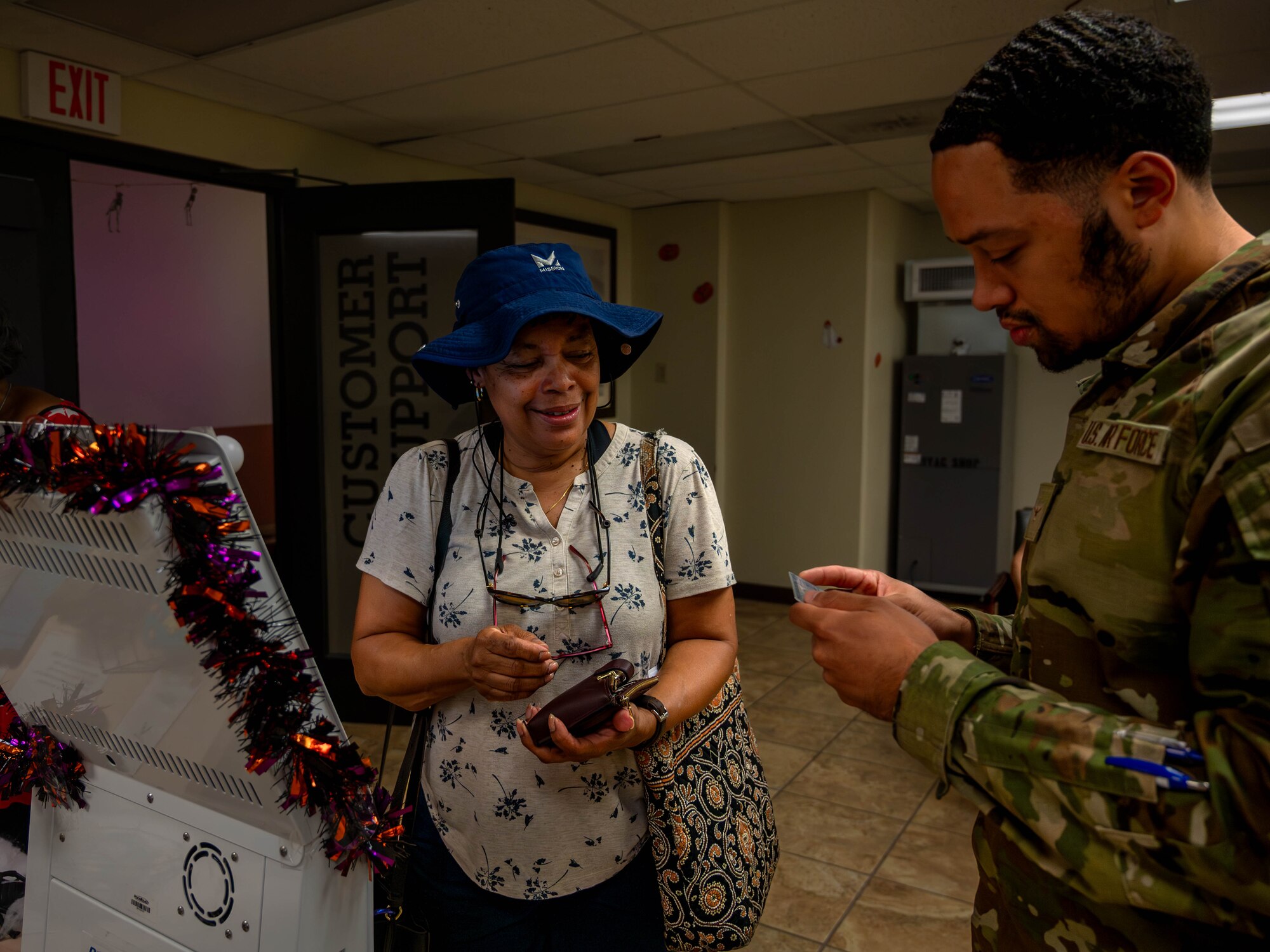 U.S. Air Force Airman Damian Robinson (right), 56th Fighter Support Squadron personnel customer support technetium, assists a retiree at the Customer Support office during a retiree appreciation event October 21, 2023, at Luke Air Force Base, Arizona.