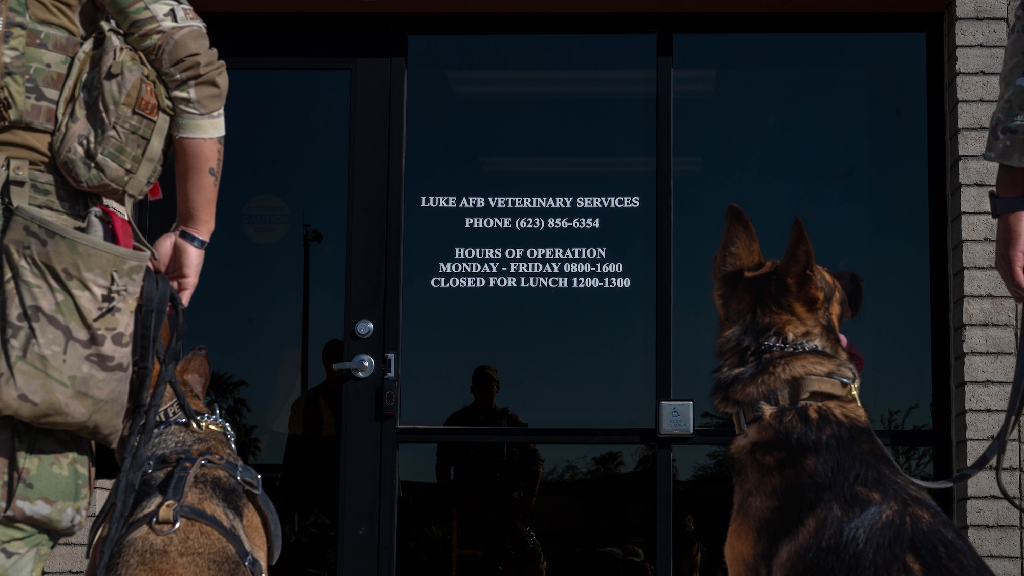Military working dogs and their handlers look at the sign for the new Luke Air Force Base Veterinary Treatment Facility, Oct. 23, 2023, at Luke Air Force Base, Arizona.