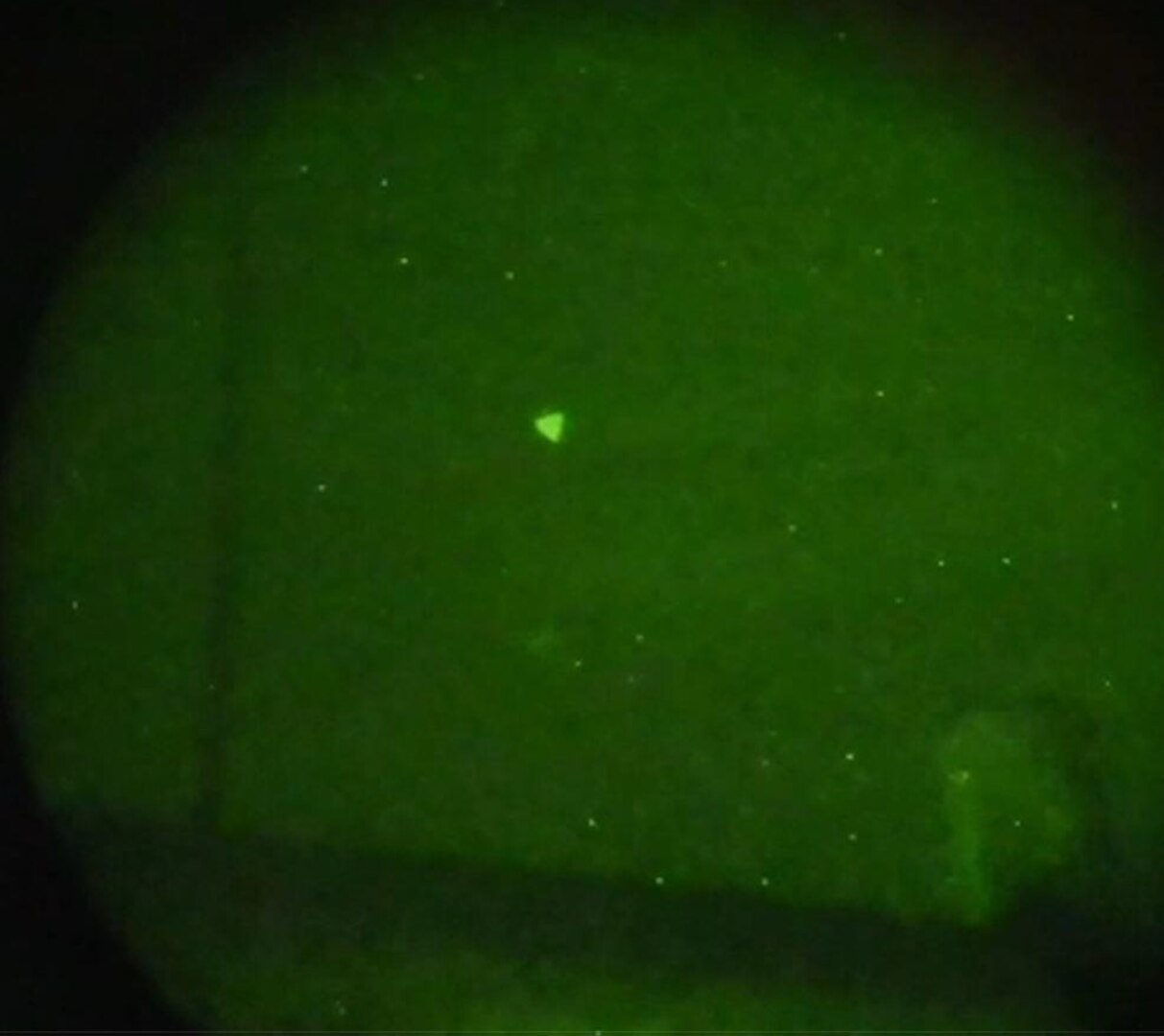 A triangular flying craft is photographed in the sky using night vision.