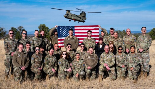  U.S. Guardians pose for a photo after a reenlistment ceremony, with a flag behind them.