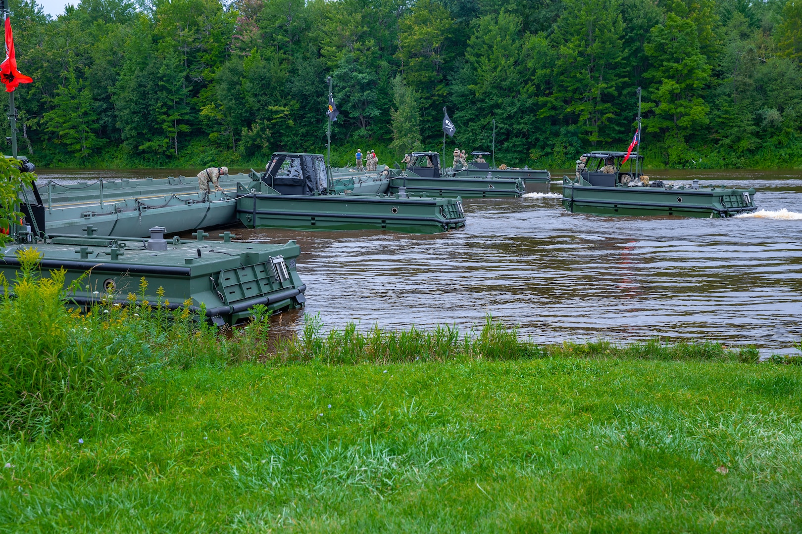 A bridge erection boat operated by Soldiers from the 250th Engineer Company (Multi-Role Bridge Company), 192nd Engineer Battalion, Connecticut Army National Guard, pulls away from a section of an improved ribbon bridge at Fort Drum, New York, Aug. 10, 2023.