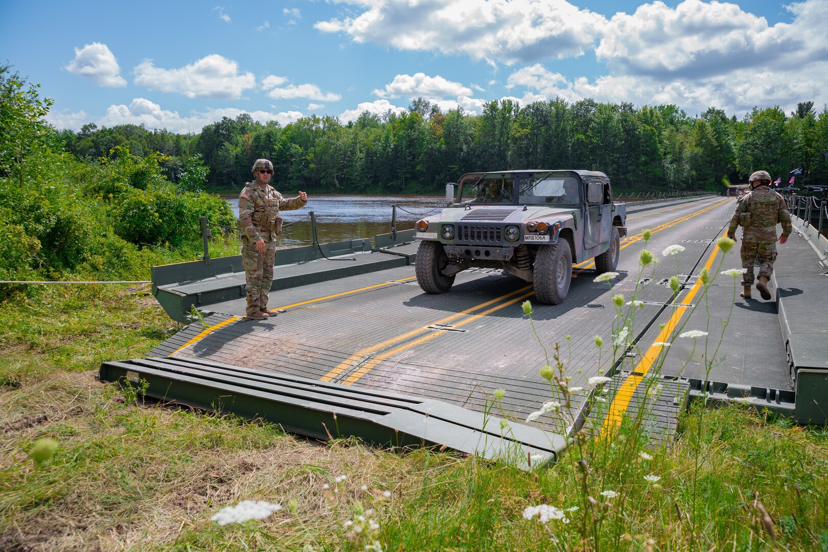 A Connecticut Army National Guard High Mobility Multipurpose Wheeled Vehicle is directed over an improved ribbon bridge by a Connecticut Army National Guard Soldier at Fort Drum, New York, Aug. 11, 2023. Soldiers from the 250th Engineer Company set up the bridge so units of the 143rd Regional Support Group could conduct a wet gap crossing during their annual training.