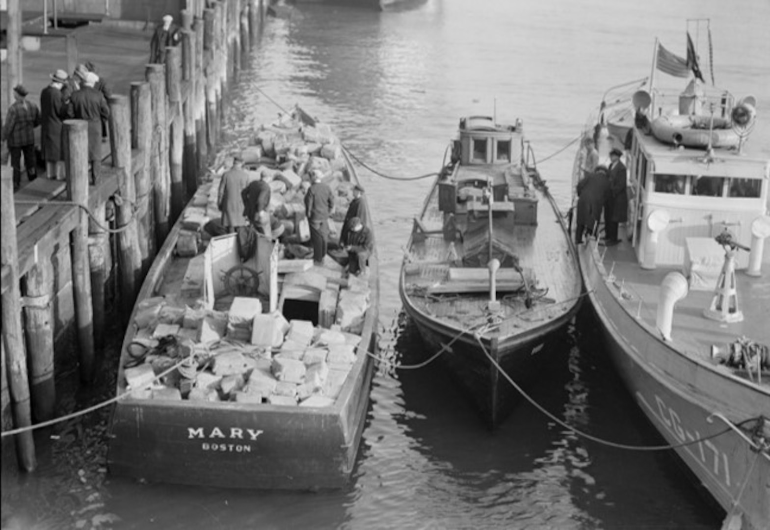 An apprehended rumrunner loaded with liquor shown with a Coast Guard 75-foot patrol boat on the docks in Boston. (Courtesy of Boston Public Library)