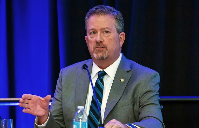 A person behind a microphone makes a gesture with his hand.