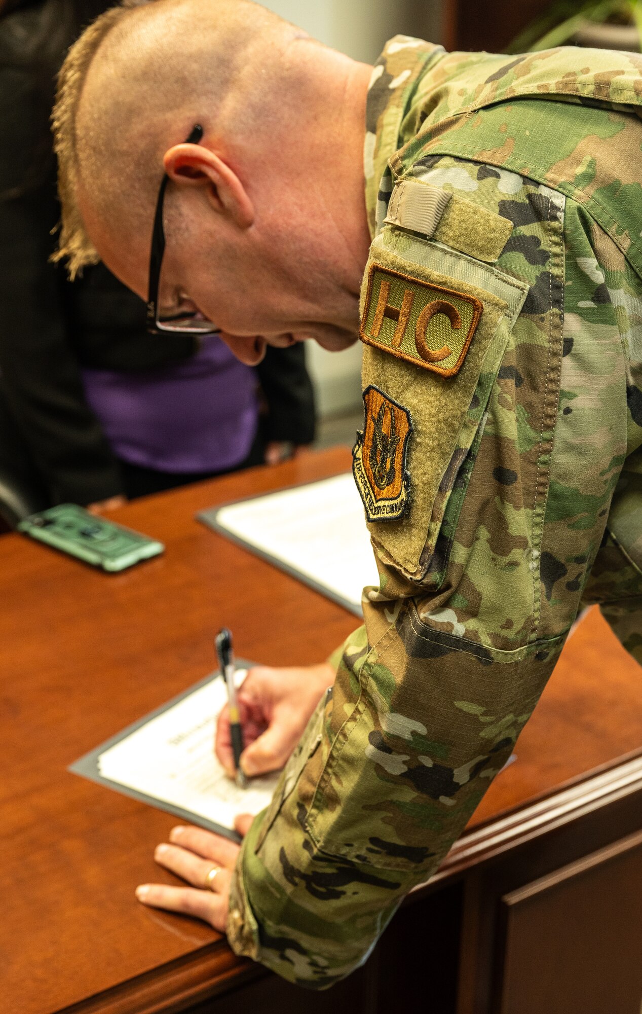 Caucasian man with military occupational uniform signs an affirmation.