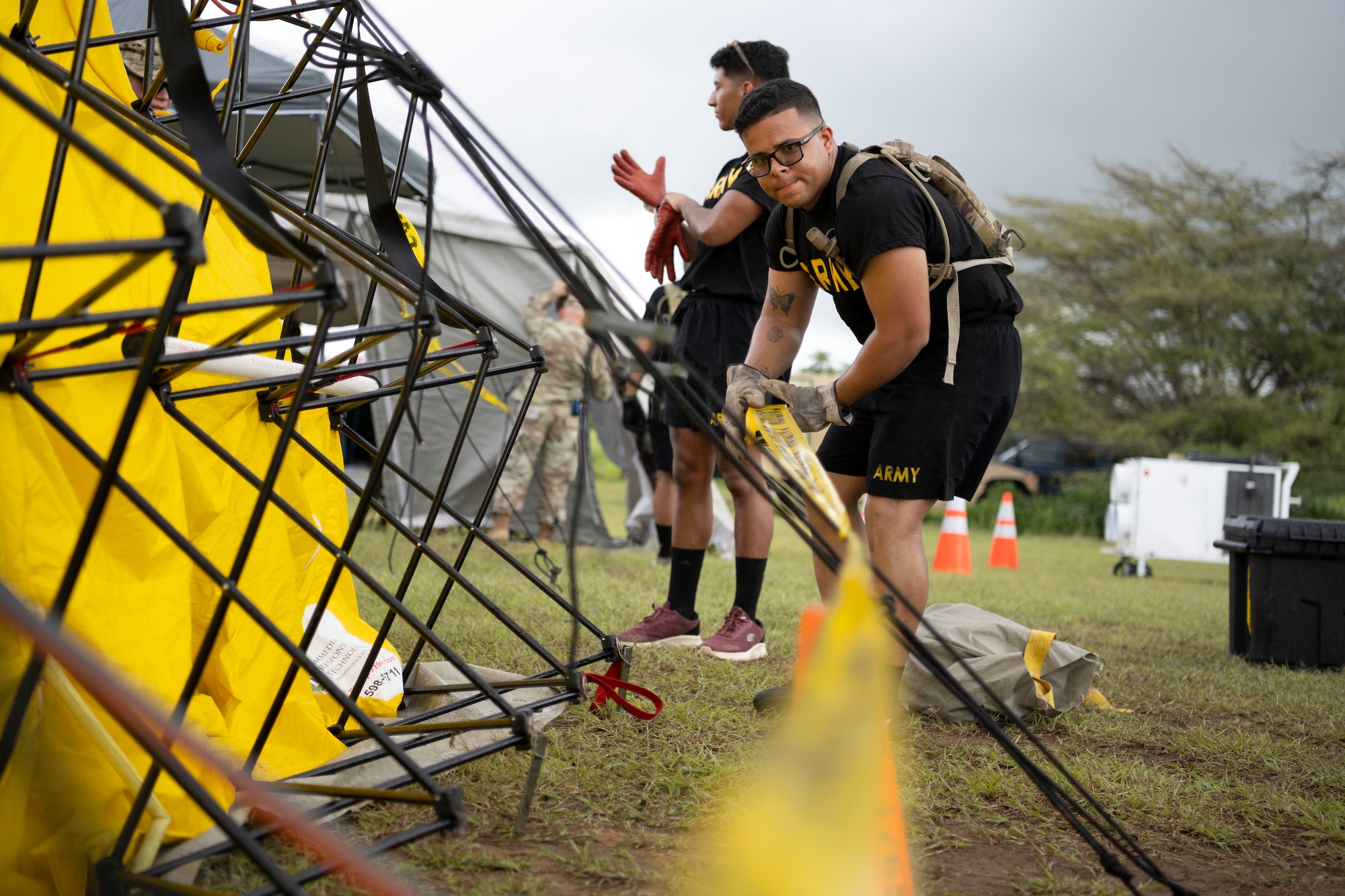 A U.S. Soldier assigned to the Puerto Rico Army National Guard rolls out caution tape around a tent during a collective training exercise at Camp Santiago Joint Training Center, Salinas, Puerto Rico, Aug. 10, 2023. The exercise allowed service members assigned to the 156th Medical Group, 123rd Medical Group and the Puerto Rico Army National Guard to exchange knowledge and implement the National Guard CBRN Response Enterprise Information Management System, which assists with accelerating data collection from search and extraction teams in emergency events. (U.S. Air National Guard photo by Master Sgt. Rafael D. Rosa)