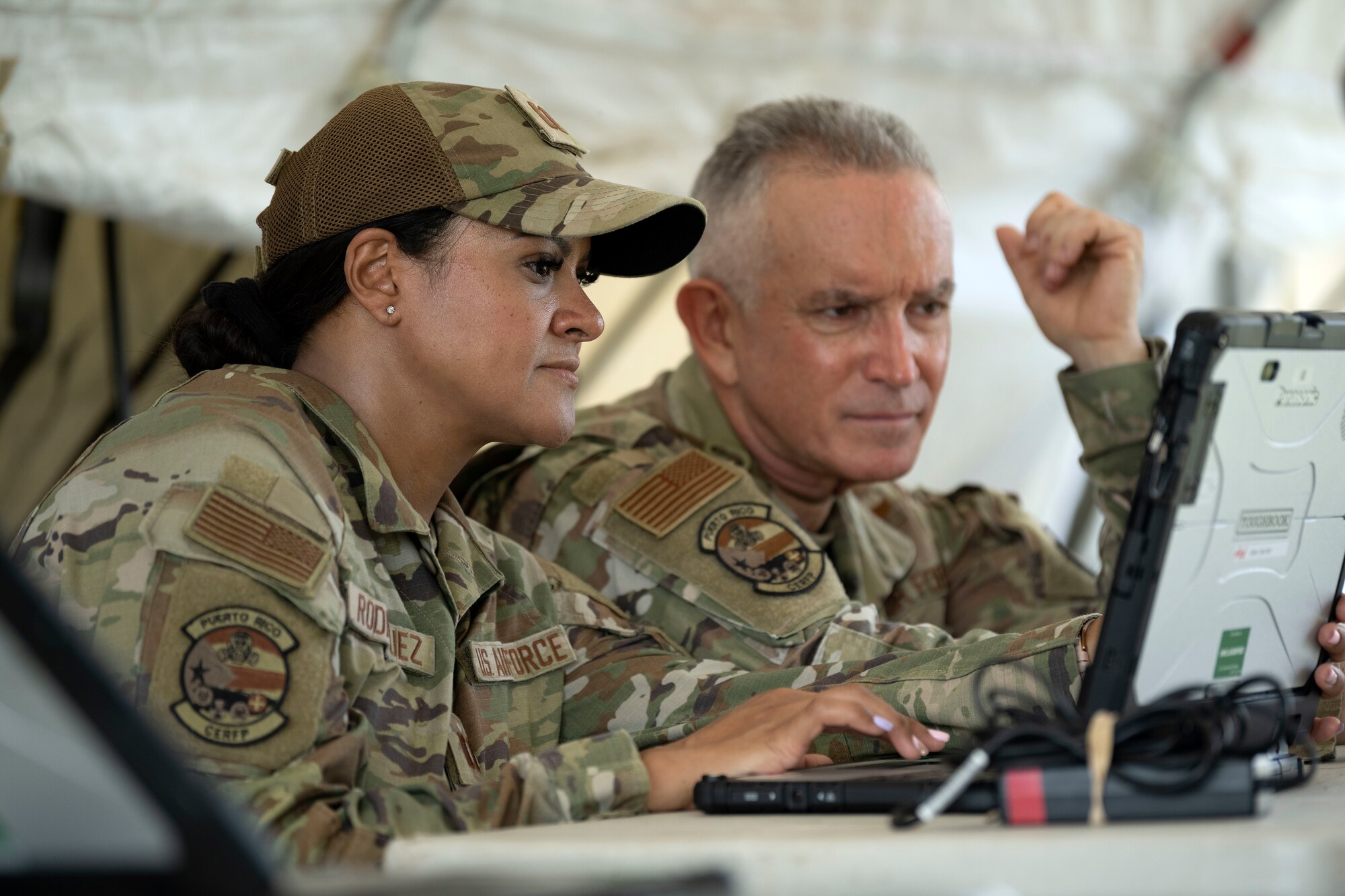 From left, U.S. Air Force Capt. Ileana Rodriguez, a pharmacist and Lt. Col. Robert Shleier, a medical provider, both assigned to the 156th Medical Group, Detachment 1, operate a computer during a collective training exercise at Camp Santiago Joint Training Center, Salinas, Puerto Rico, Aug. 10, 2023. The exercise allowed service members assigned to the 156th Medical Group, 123rd Medical Group and the Puerto Rico Army National Guard to exchange knowledge and implement the National Guard CBRN Response Enterprise Information Management System, which assists with accelerating data collection from search and extraction teams in emergency events. (U.S. Air National Guard photo by Master Sgt. Rafael D. Rosa)