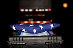 A folded American flag rests on a black case.