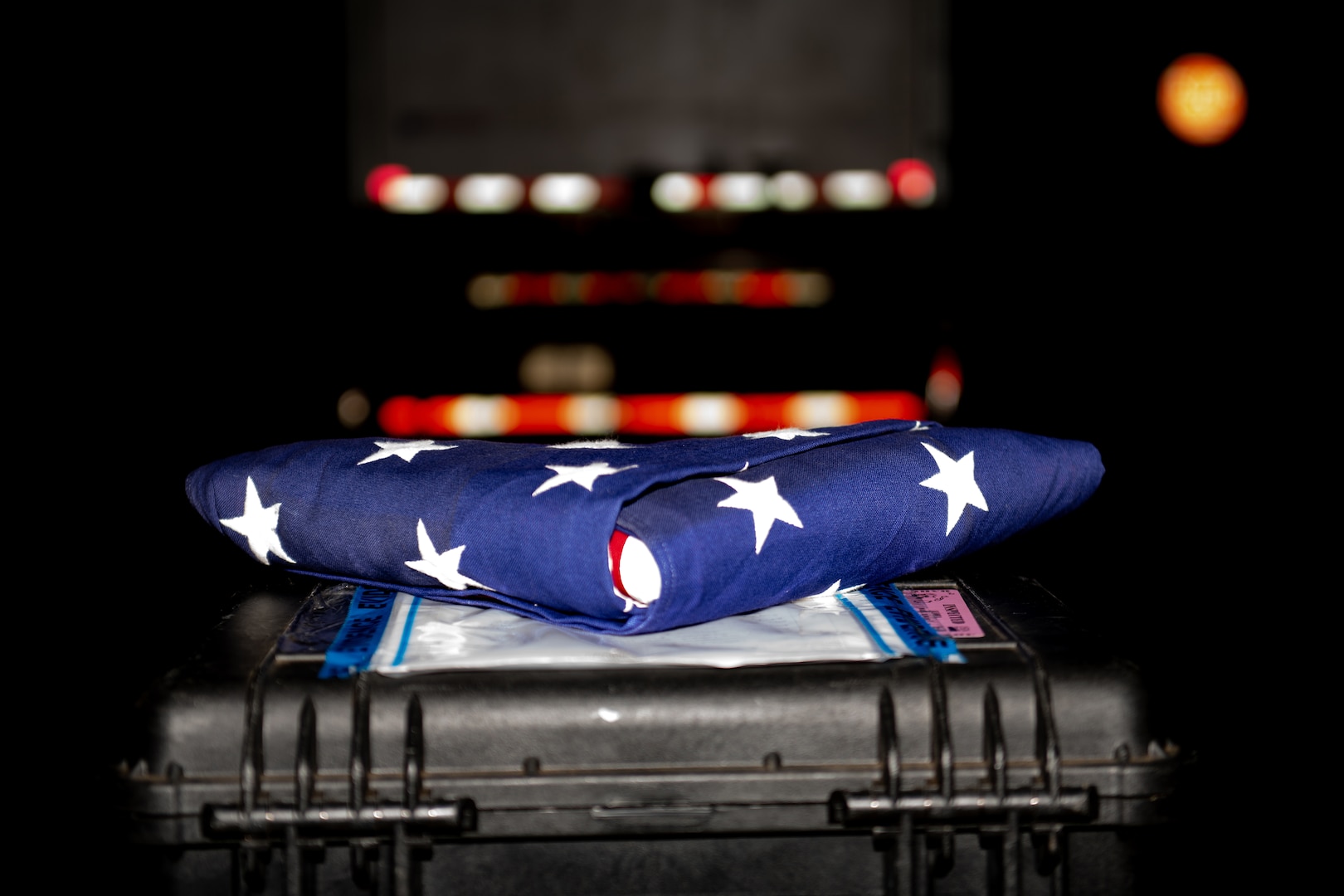 A folded American flag rests on a black case.