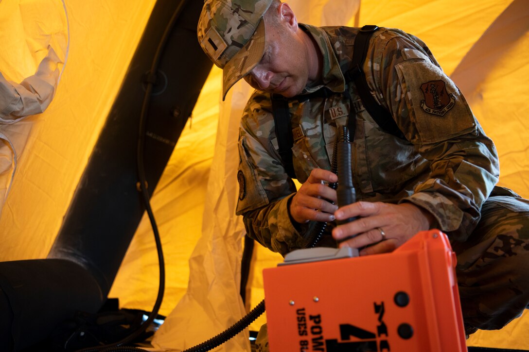 A U.S. Airman assigned to the 123rd Medical Group, Detachment 1, connects wiring inside an inflatable tent during a collective training exercise at Camp Santiago Joint Training Center, Salinas, Puerto Rico, Aug. 10, 2023. The exercise allowed service members assigned to the 156th Medical Group, 123rd Medical Group and the Puerto Rico Army National Guard to exchange knowledge and implement the National Guard CBRN Response Enterprise Information Management System, which assists with accelerating data collection from search and extraction teams in emergency events. (U.S. Air National Guard photo by Master Sgt. Rafael D. Rosa)