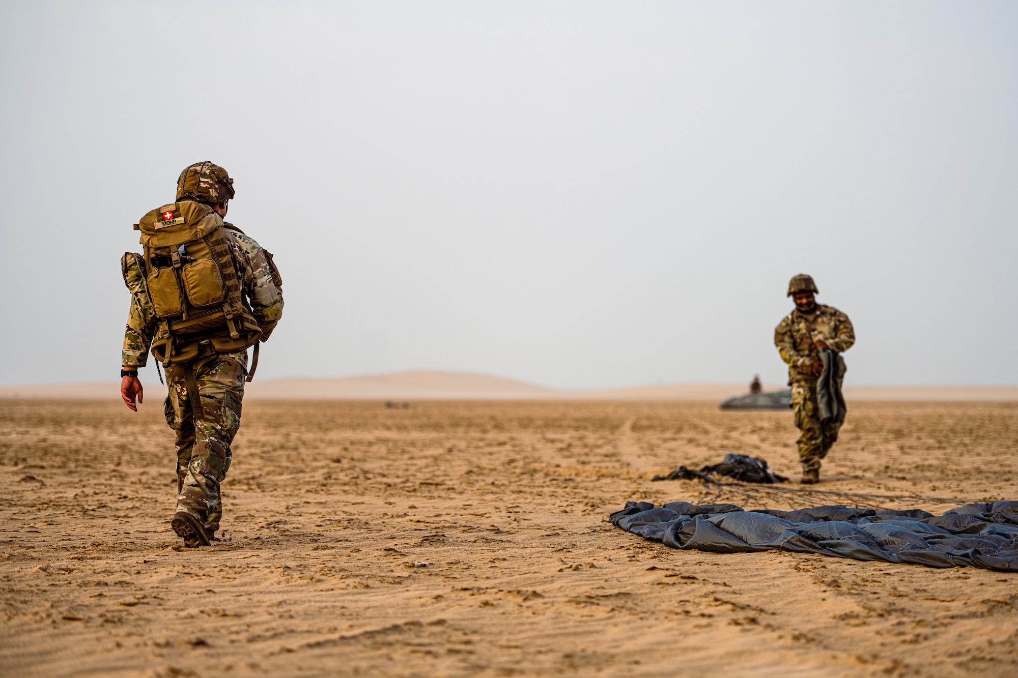 Military members walking through the desert