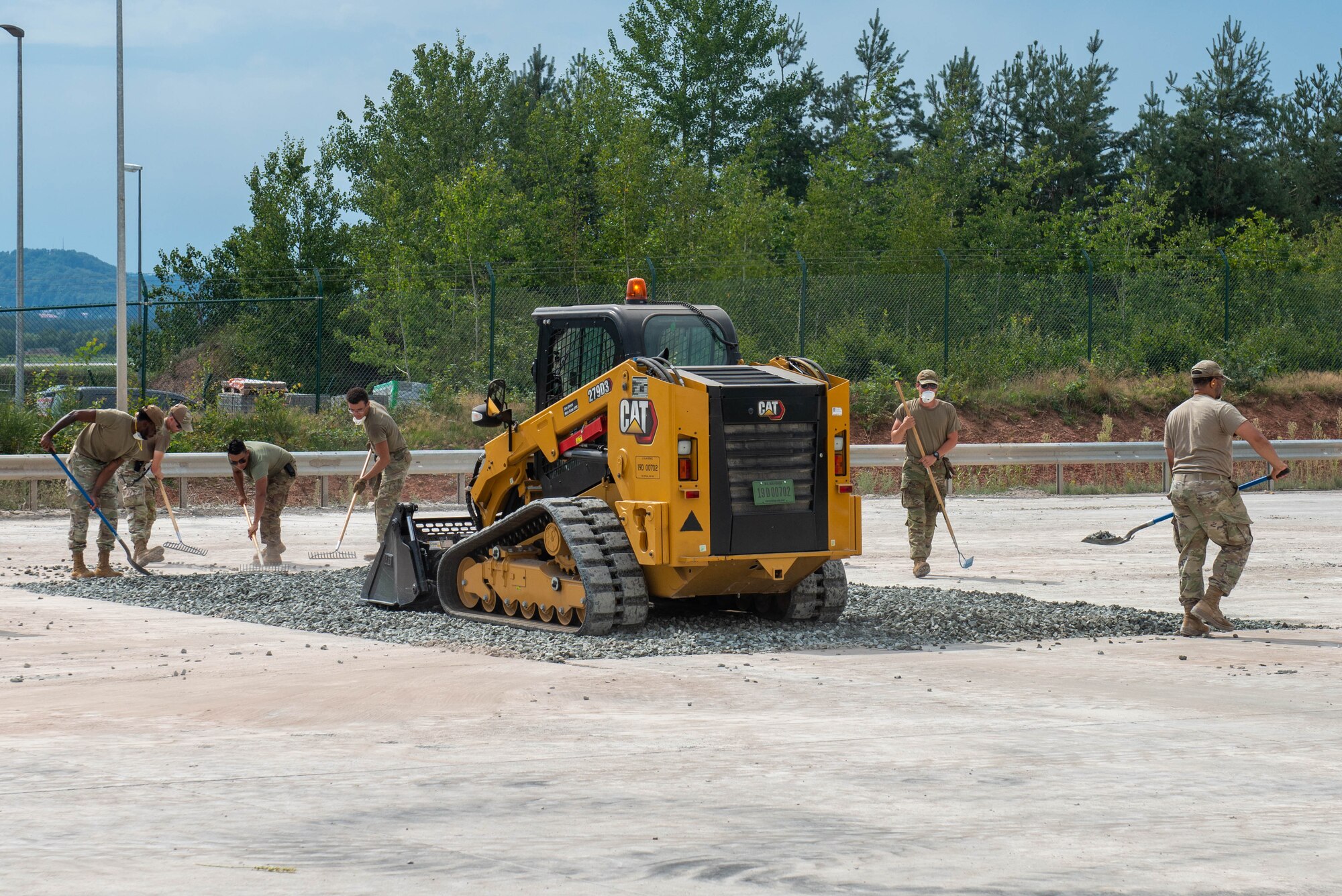 Airmen push crushed rock into a crater during an airfield repair demonstration