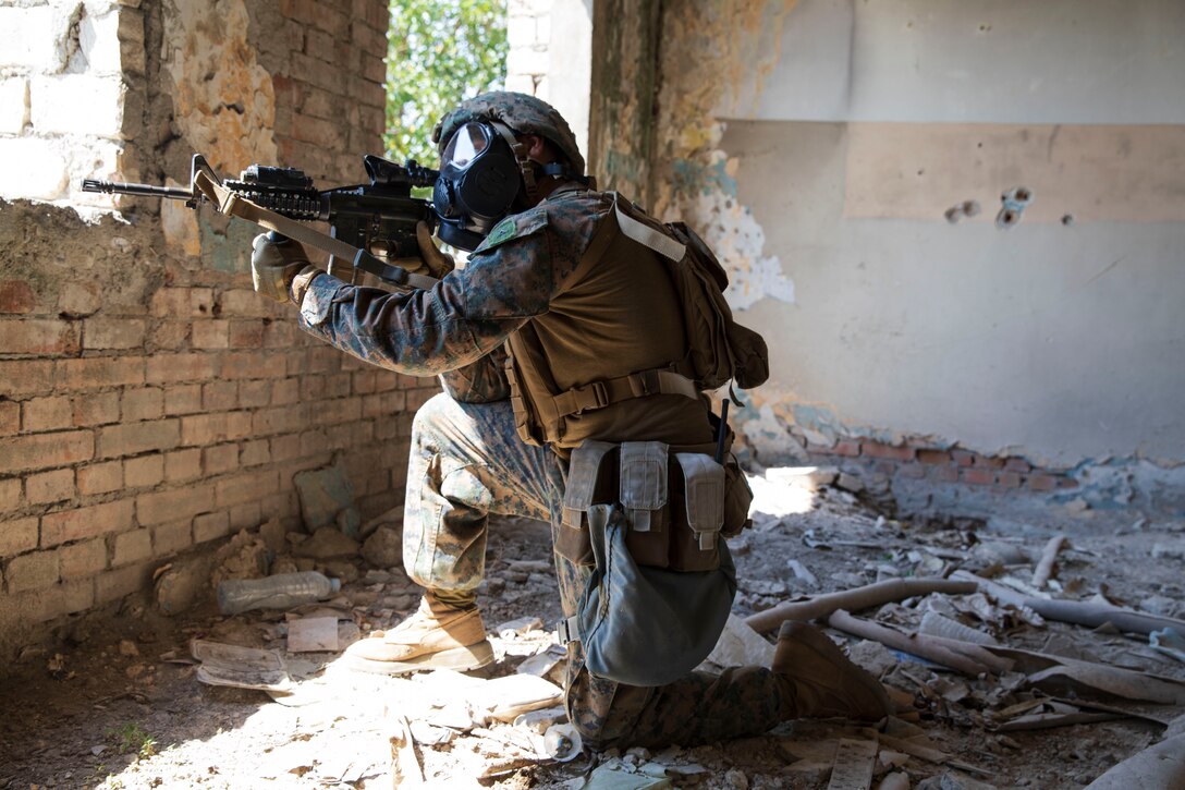 A Marine holding a weapon takes a knee while providing security during a training exercise.