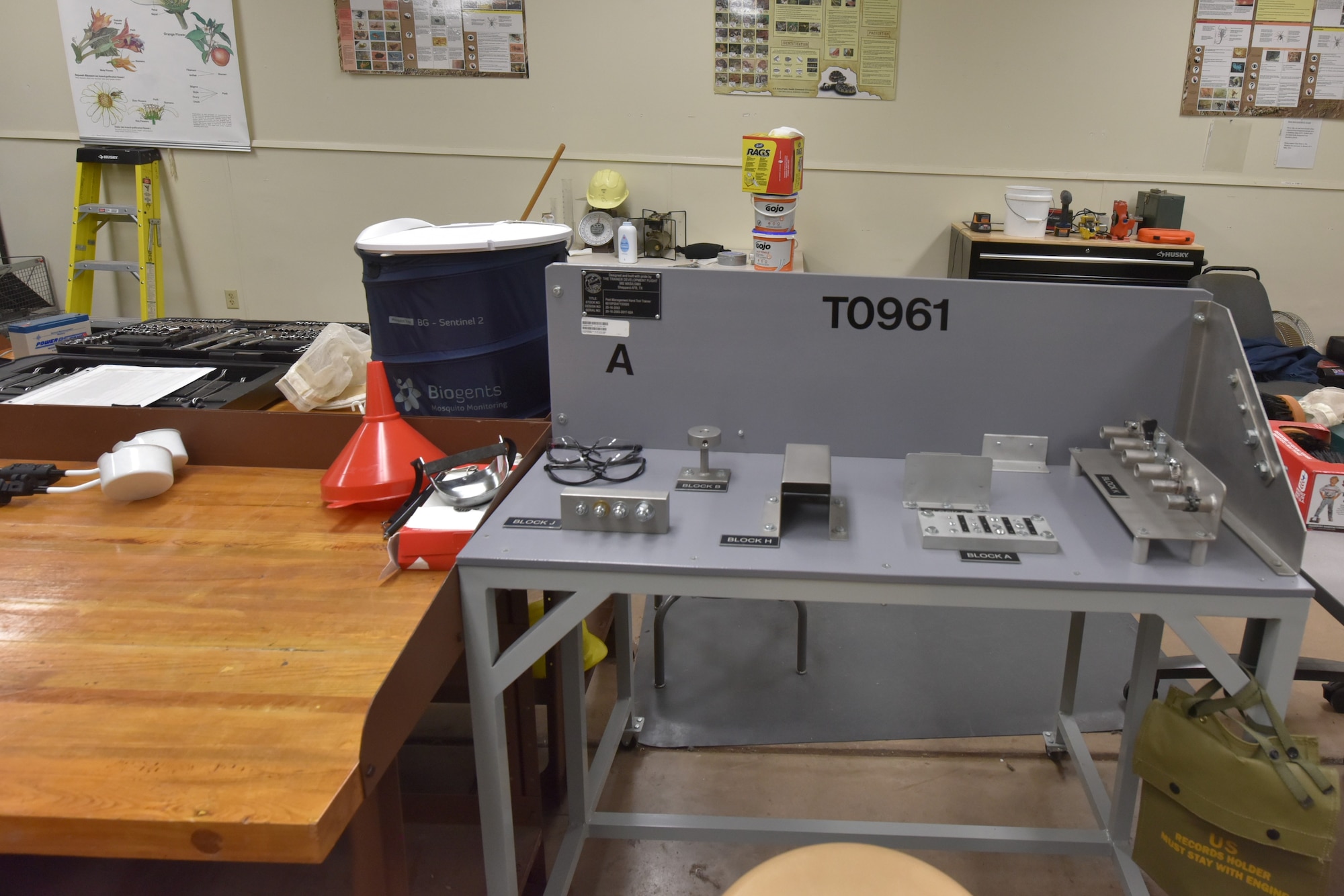 A gray table with nuts and bolts attached used to train students to use tools