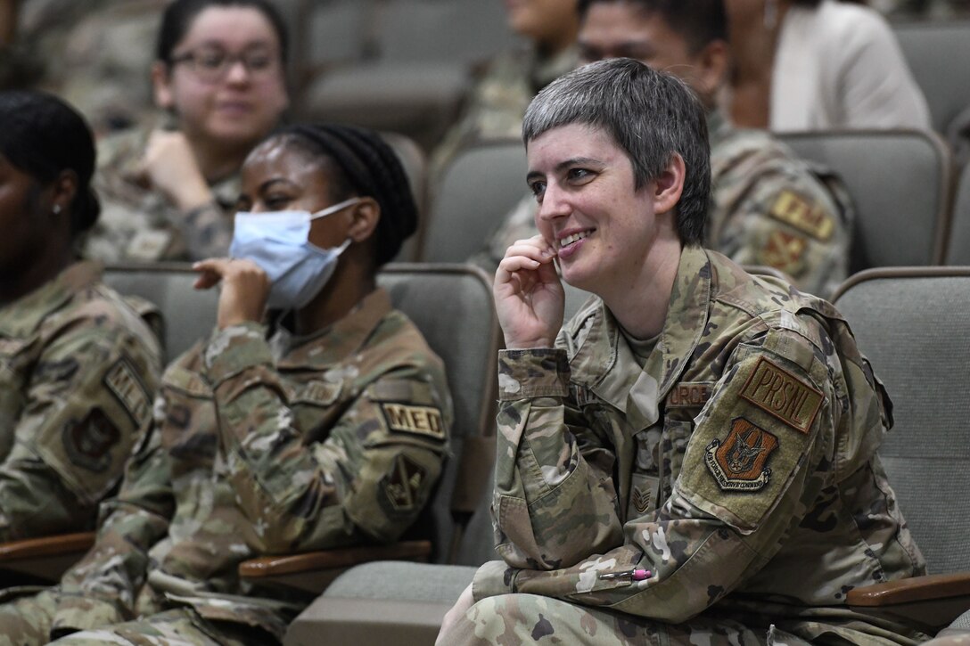 Military members in uniform listen during a meeting.