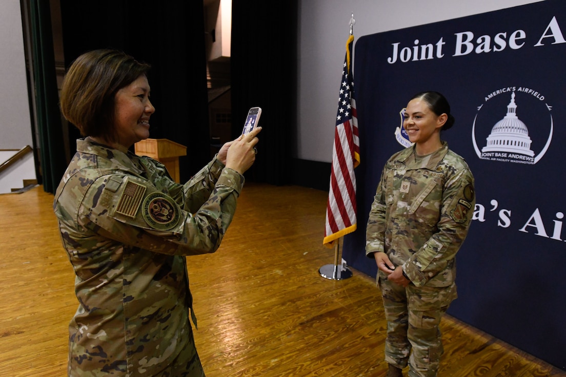 Two women in uniform take photos.