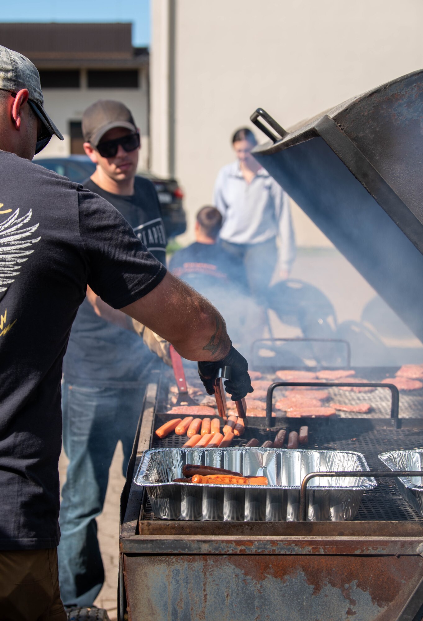 Volunteers grill burgers and hotdogs on barbecue.