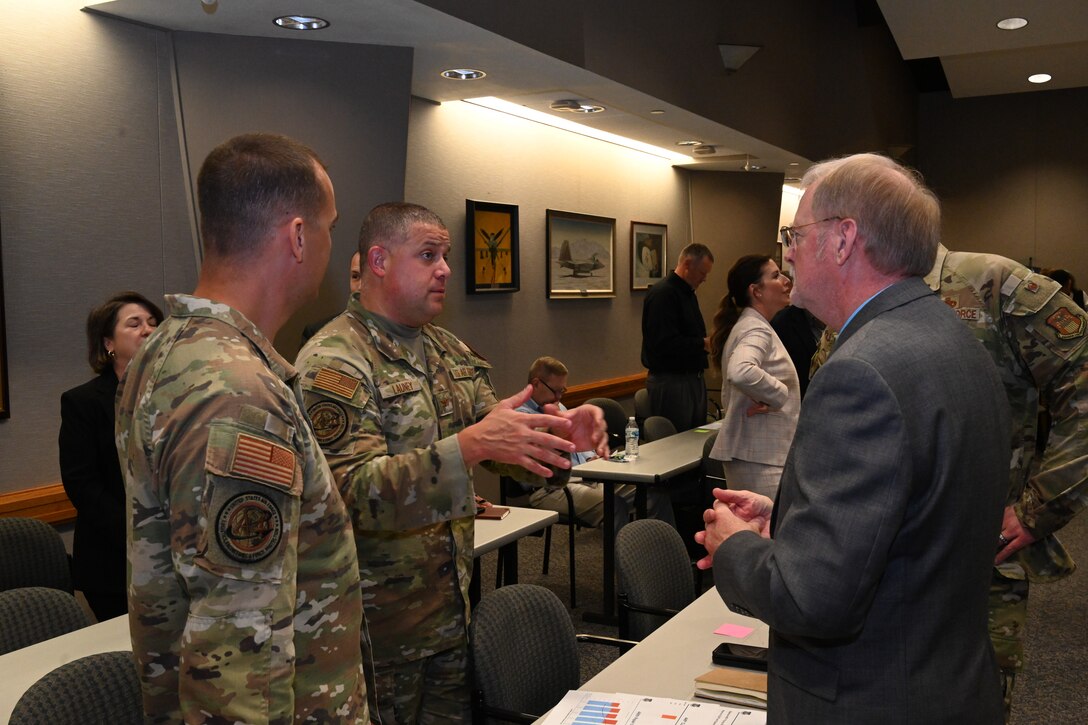 Photo of Airmen and a civilian having a discussion.