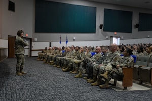 Military members in uniform meet in a theater.