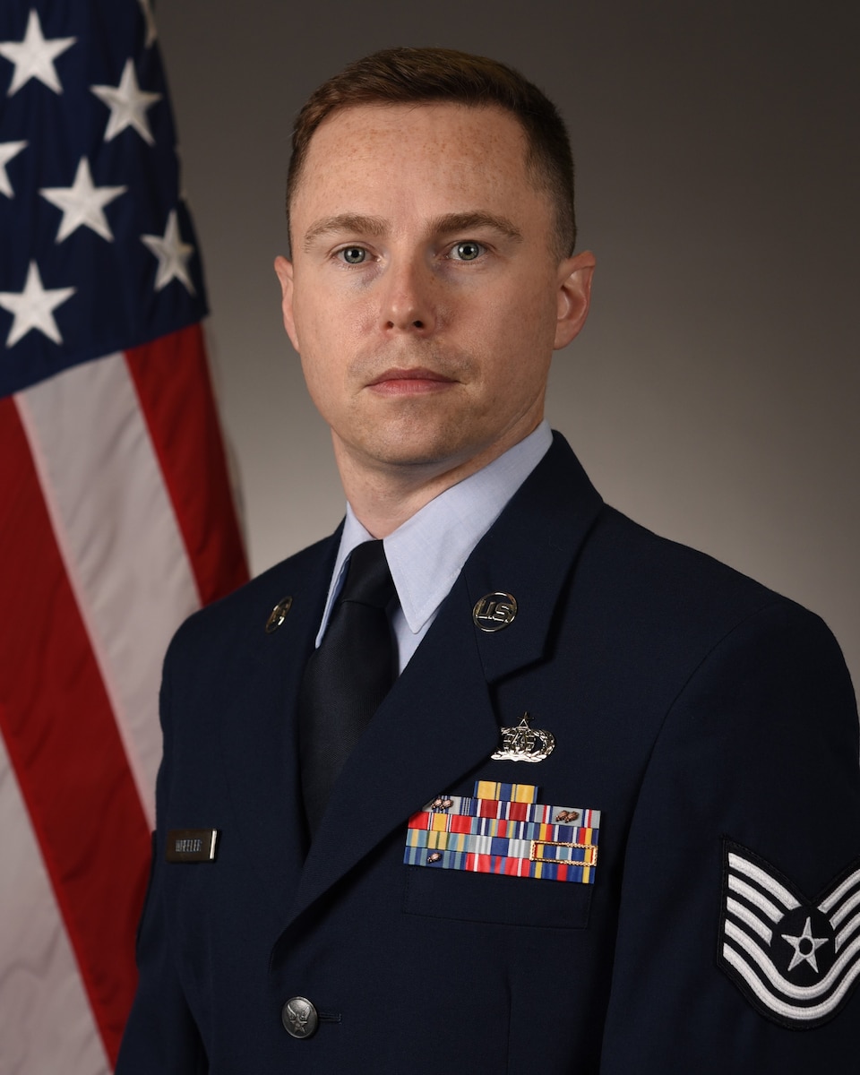 Official Photo of TSgt Mark Wheeler with American flag over right shoulder