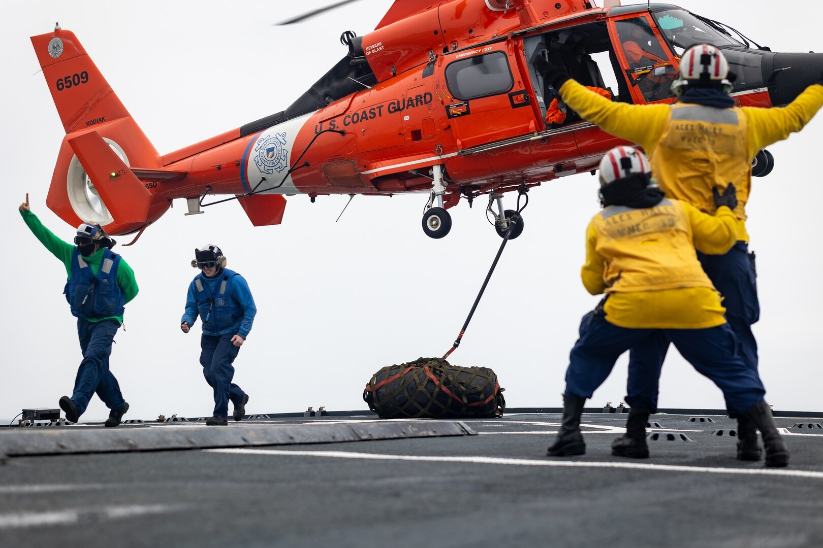 Alex Haley crewmembers assist in the landing of a MH-65 Dolphin helicopter from Air Station Kodiak in the Bering Sea, July 16, 2023. The Alex Haley is a 282-foot Medium Endurance Cutter that performs search and rescue, fisheries law enforcement and vessel safety inspections across Alaska and has been home-ported in Kodiak since 1999. U.S. Coast Guard Photo by Petty officer First Class Jasen Newman.