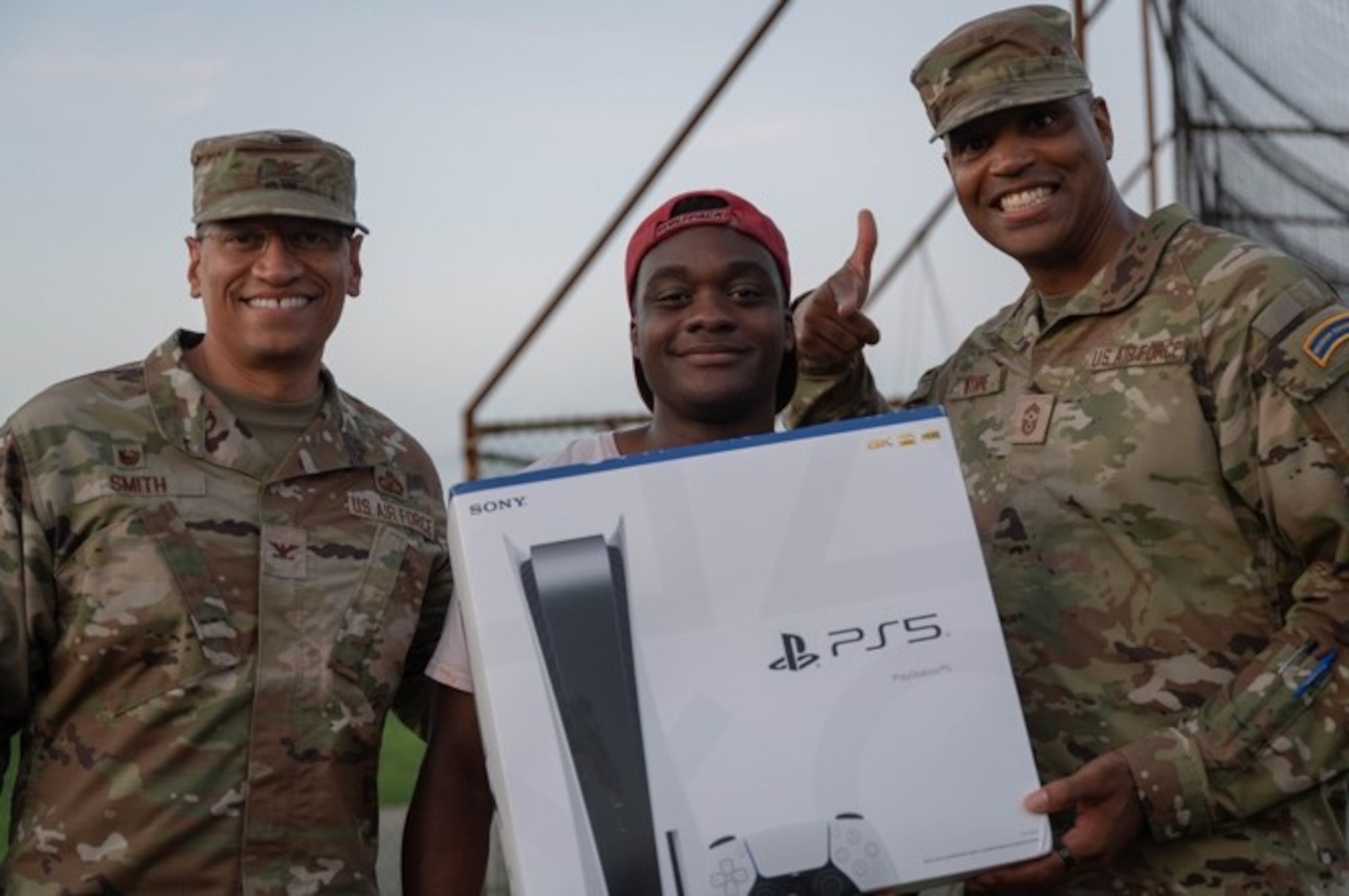 U.S. Air Force Col. Anthony L. Smith, Joint Base McGuire-Dix-Lakehurst commander and the 87th Air Base Wing commander, and Chief Master Sgt. Michael Wynne, 87th ABW command chief master sergeant, pose with a service member during the Cars and Cookout event at JB MDL, N.J., Aug. 17, 2023. The Dorm Council hosted the event to highlight on-base activities available for service members and boost morale. (U.S. Air Force photo by Airman 1st Class Aidan Thompson)
