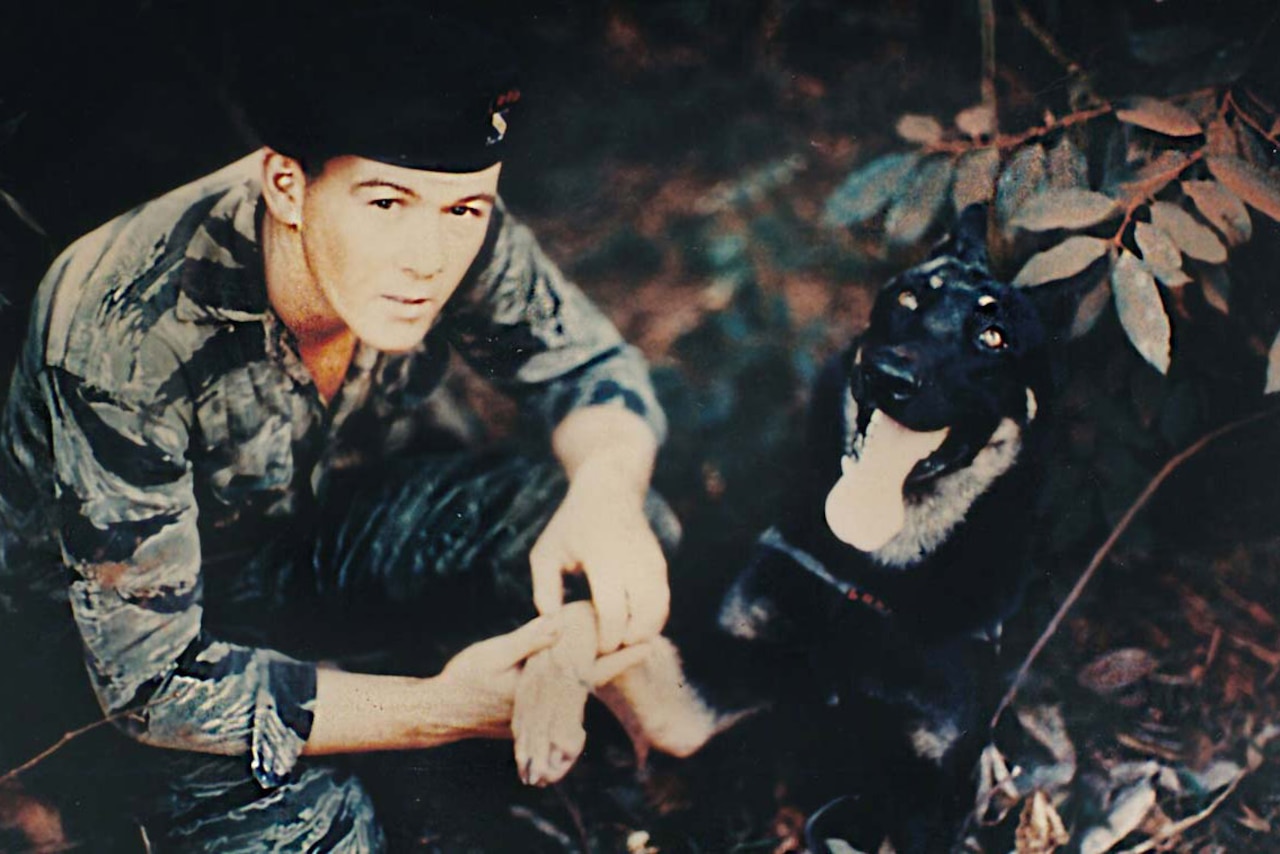 A soldier poses with his dog.