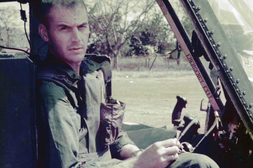 A helicopter pilot sits at the controls.