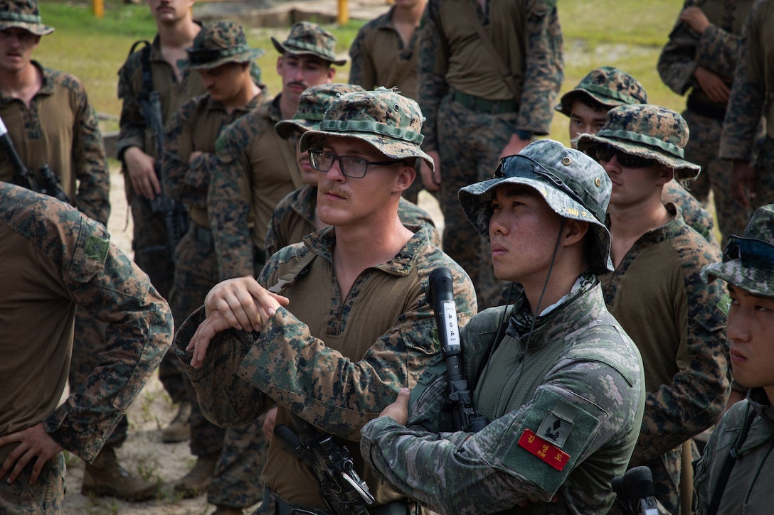 U.S Marines with 3rd Battalion, 5th Marine Regiment, 1st Marine Division and Republic of Korea (ROK) infantry Marines, listen during a range safety brief, as a part of Korea Marine Exchange Program (KMEP) 23.3 on August 4, 2023, at Rodriguez Live Fire Complex, Gyeonggi-do, Republic of Korea. KMEP is a long-standing exercise that bolsters bi-lateral training between the two services enhancing the ROK-US standard of lethality, coordination, and mutual respect in the Indo-Pacific region. (U.S. Marine Corps photo by Cpl. Jaye Townsend)