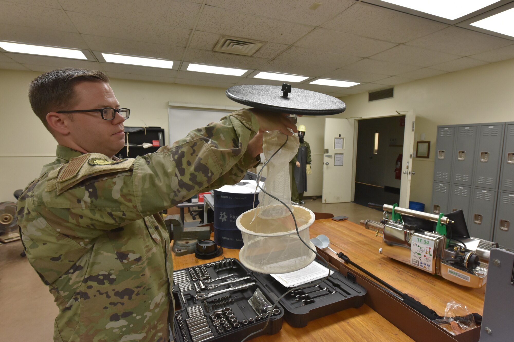 An Airmen holds up a mosquito trap
