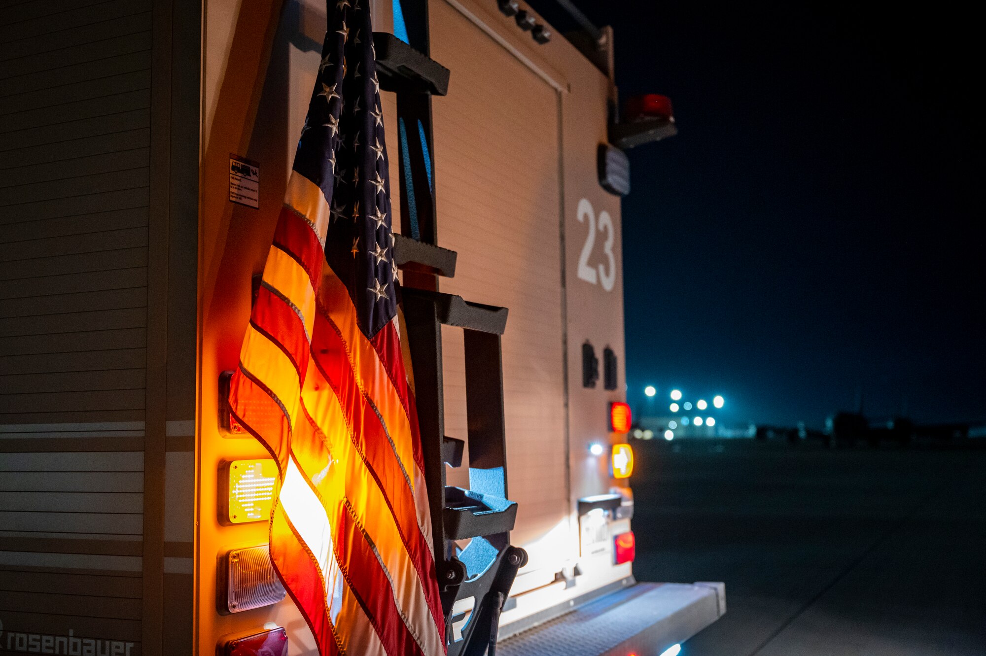 An American flag is draped on the back of a firetruck on the flight line.