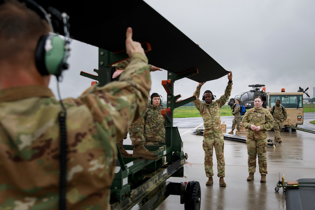 Soldiers unload helicopters at an airfield.