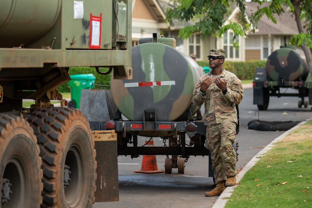 A soldier stands next to a large tank of water.