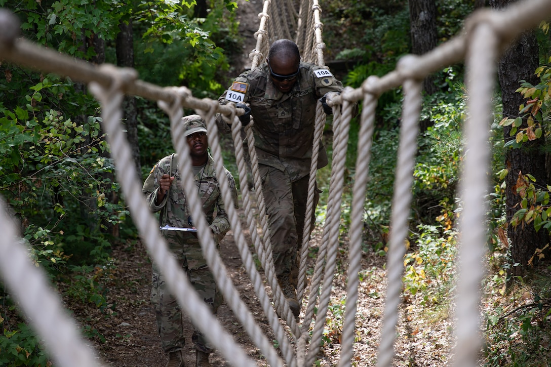 A soldier crosses a rope bridge.