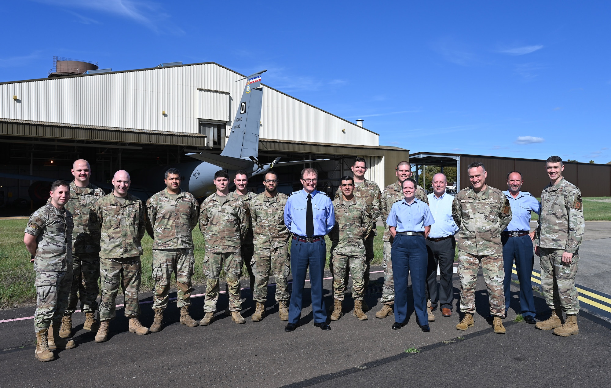 U.S. Air Force 100th Maintenance Group Airmen and leadership pose for a photo with Air Commodore Simon Strasdin, center, Royal Air Force Intelligence, Surveillance, Target Acquisition and Reconnaissance force commander, Wing Commander Sal Berris, ISTAR SO1 Rivet Joint Program, Sqn Ldr Andrew Bell, RAF Station Commander, and Steven VanderClute, U.S. Air Force Big Safari technical advisor, UK RC-135 Rivet Joint Program, during a visit to RAF Mildenhall, England, Aug. 23, 2023. The purpose of the visit was to strengthen United Kingdom-US relationships and thank 100th ARW95th Reconnaissance Squadron and 488th Intelligence Squadron Airmen for their hard work and cooperation in the joint partnership program between the RAF and U.S. Air Force reconnaissance aircraft. (U.S. Air Force photo by Karen Abeyasekere)