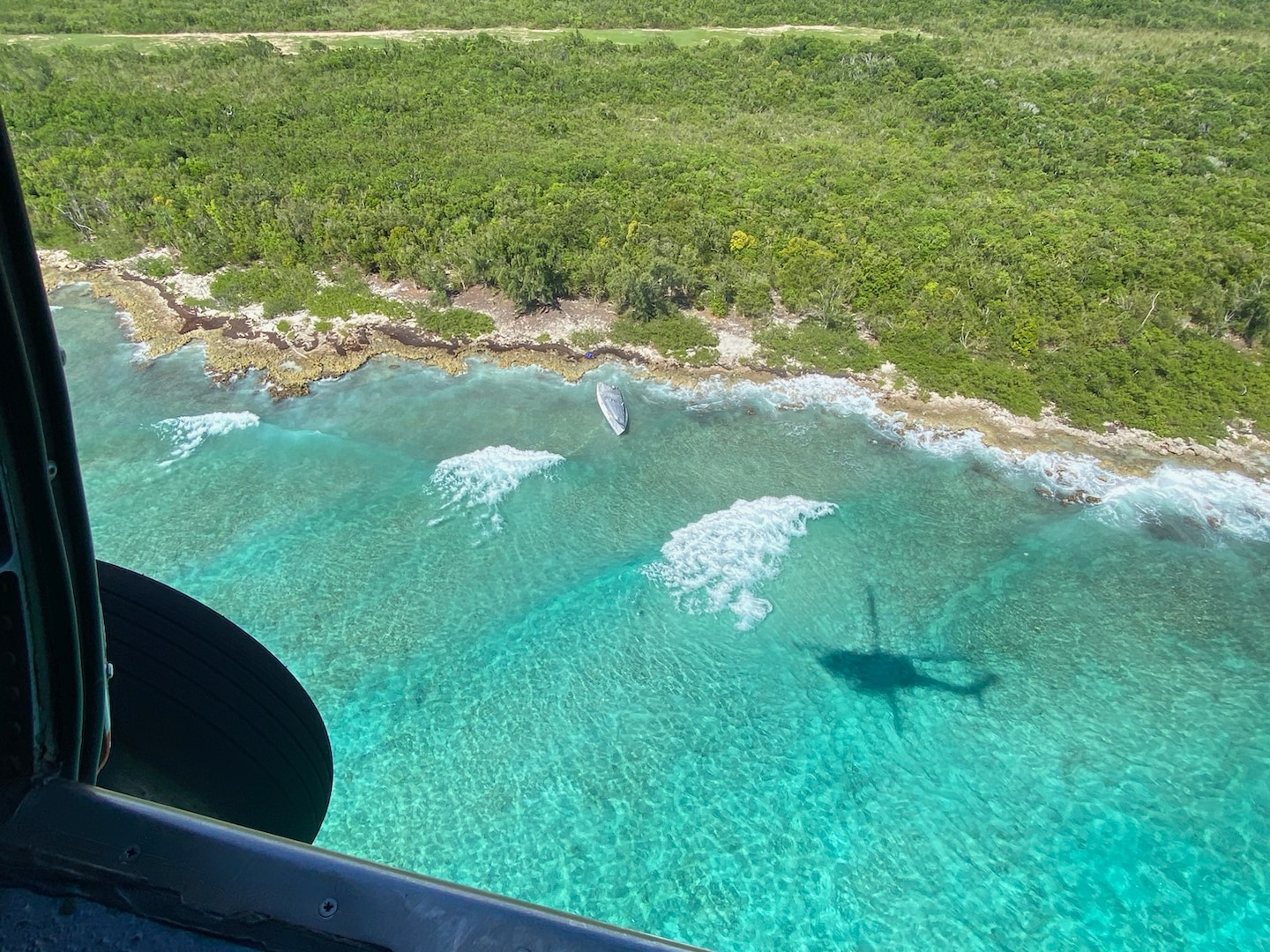 A Coast Guard MH-60T Jayhawk helicopter aircrew conducts an aerial assessment of a modified low-profile vessel aground on Mona Island, Puerto Rico, Sept. 2, 2023.  Resolve Marine cleanup crews, hired as the oil spill response organization for this case, completed the removal of 300 gallons of diesel, oily water waste and two cubic yards of oiled debris from the vessel’s tanks and interior Sept. 5, 2023.  (U.S. Coast Guard photo)