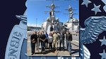 Photo is of a group of people standing on a Navy ship deck.