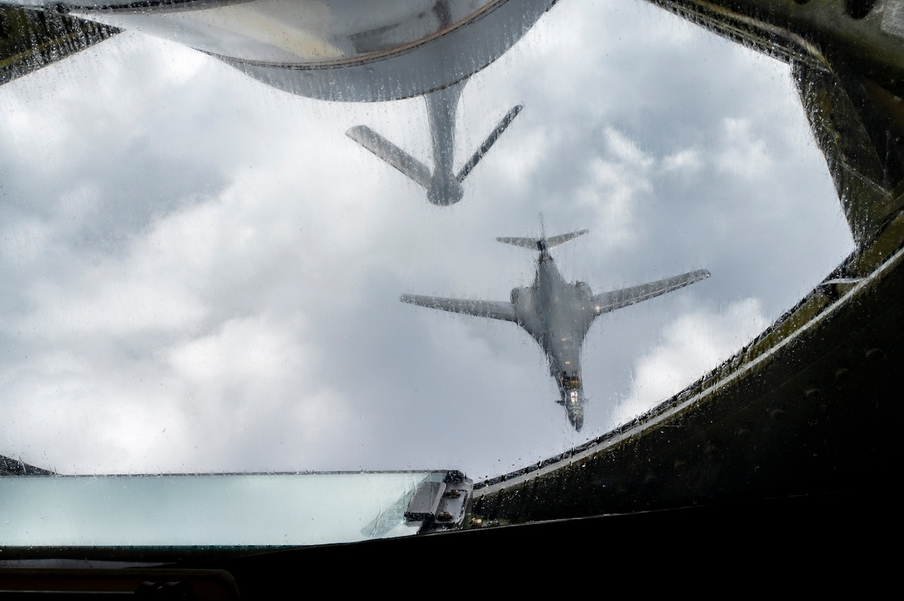 A military aircraft departs after an in-air refueling. The aircraft can be seen flying away from the refueling aircraft's window.