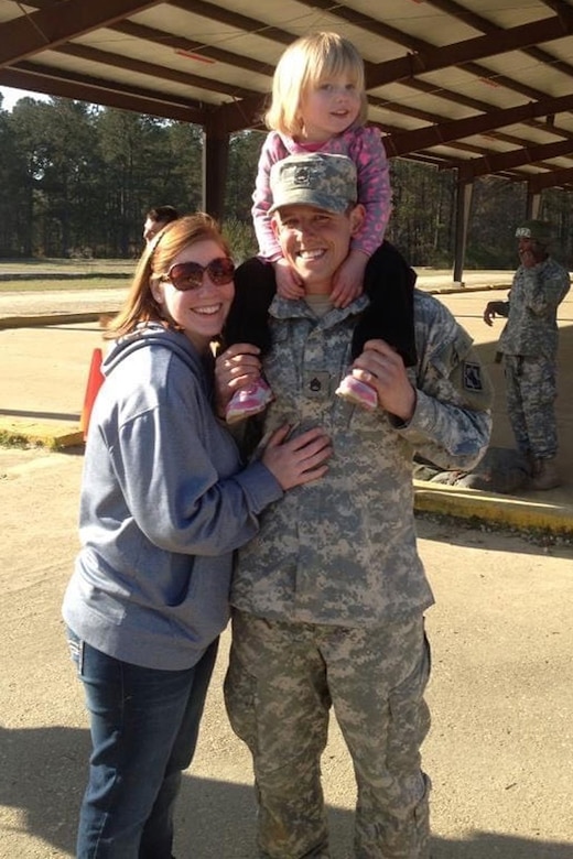 A person stands beside a soldier, who has a small child on their shoulders.