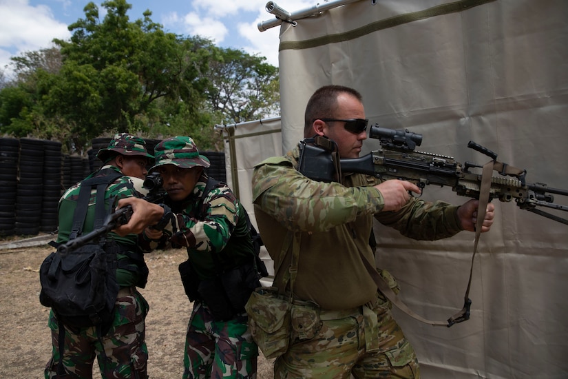 Troops with guns practice military tactics.